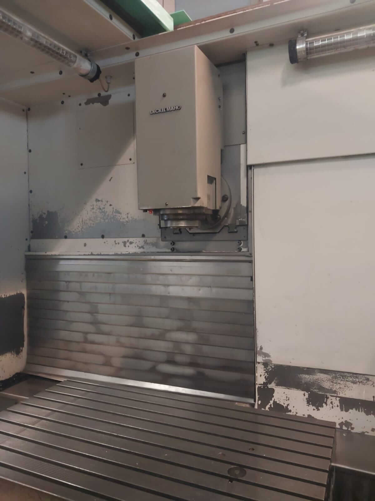 Detailansicht einer CNC-Fräsmaschine von Deckel Maho mit stabilem Arbeitstisch und Gehäuseteil.