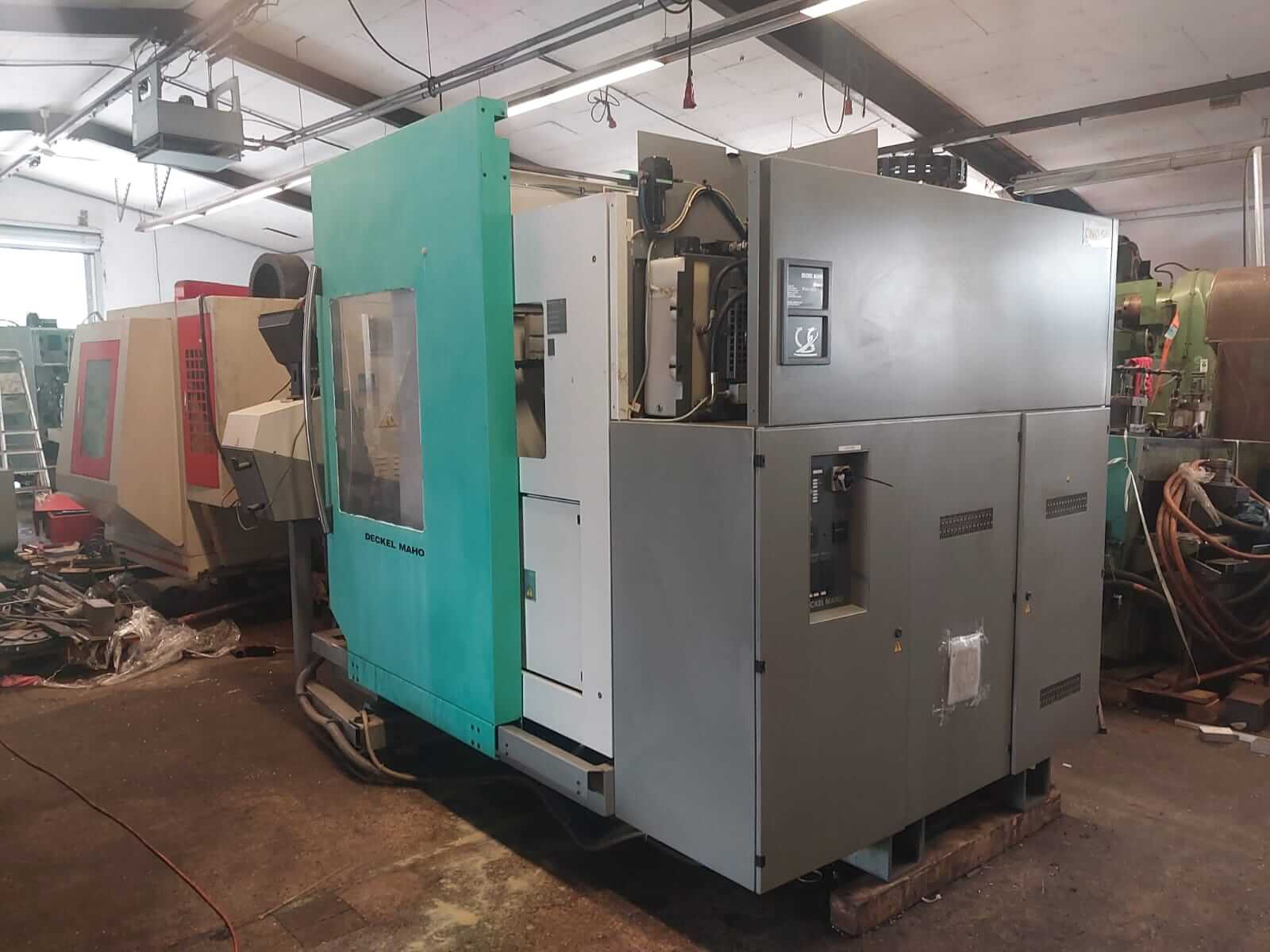 Eine große, gebrauchte CNC-Fräsmaschine in einer industriellen Werkstatt mit weiteren Maschinen im Hintergrund.